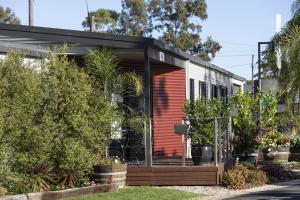 a house with a red facade with plants and trees at BIG4 Albury Tourist Park in Albury
