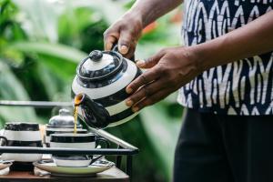 a person holding a tea kettle on a table at Villa Republic Bandarawela (04 bedroom) in Bandarawela +60 photos