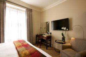 a hotel room with a bed and a couch and a tv at The Angel Hotel in Abergavenny