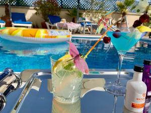 two cocktails sitting on a table next to a swimming pool at Harmonia Blue Mediterranean Modern Luxury HEATED POOL Prime Location in Polis Chrysochous