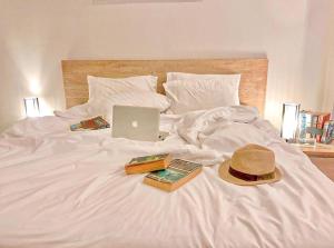 a bed with a hat and books and a laptop on it at Lemonade Phuket Hotel -SHA Plus in Chalong