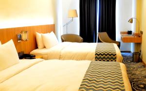 Una habitación de hotel con dos camas y un escritorio. en Louis Kienne Hotel Simpang Lima, en Semarang