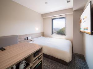 ein kleines Schlafzimmer mit einem Bett und einem Fenster in der Unterkunft Super Hotel Anan Tomioka in Anan