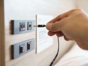 a person plugging a cord into an electrical outlet at Super Hotel Anan Tomioka in Anan