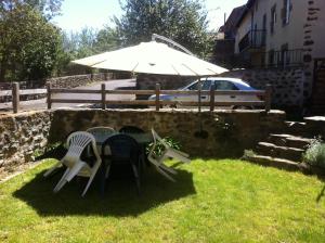 - une table et des chaises dans une cour avec un parasol dans l'établissement maison Mouilhade, à Chaspuzac