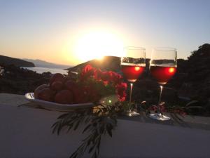 two glasses of wine and a bowl of fruit on a table with the sunset at Villa Costa Studios in Vathi
