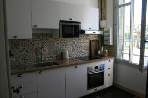 kuchnia z białymi szafkami, zlewem i kuchenką mikrofalową w obiekcie QUAI SOUCHET w mieście Libourne