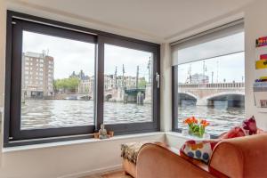 a room with windows with a view of a river at Houseboat Ark van Amstel in Amsterdam