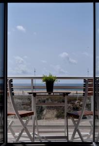 ナザレにあるApartamento T2 Vista Marの鉢植えのテーブル、ビーチチェア2脚