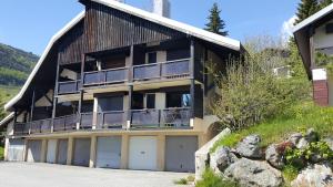 an apartment building with a balcony and two garage at Le Skidoux in LʼHuez