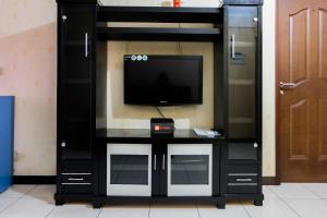 a black entertainment center with a flat screen tv at 2BR Apartment at 18th Floor Great Western By Travelio in Tangerang