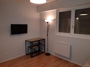a room with a lamp and a television on a wall at Charmant Studio in Metz
