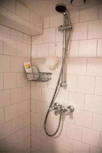 a shower in a white tiled bathroom at Houseboat Ark van Amstel in Amsterdam