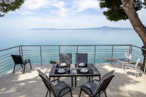 a table and chairs on a balcony with a view of the water at Naftilos Blue View retreat in Avia