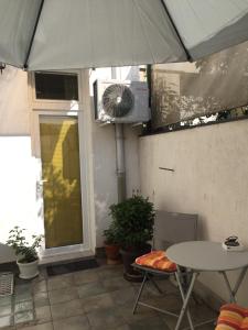 - une terrasse avec une table, un parasol et un ventilateur dans l'établissement Crown Street Garden Studio, à Belgrade