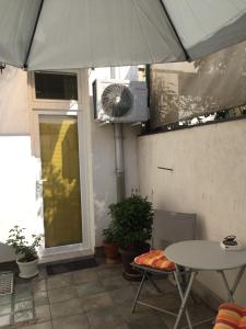 a patio with a table and an umbrella and a fan at Crown Street Garden Studio in Belgrade