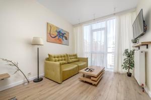 ein Wohnzimmer mit einem gelben Sofa und einem Tisch in der Unterkunft Студия в стиле лофт с прекрасным видом на город и красивые закаты! in Odessa