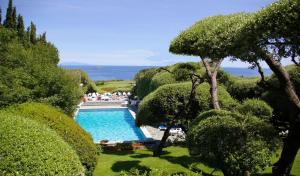 a swimming pool in a garden with bushes and trees at Hôtel Pietracap in Bastia
