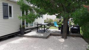 a patio with a table and chairs next to a house at Mobil home récent clim 3ch Camping3* piscine in Argelès-sur-Mer