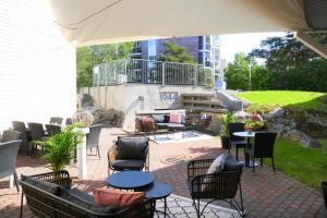 a patio with chairs and tables and an umbrella at Hotel Kalliohovi in Rauma