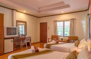 Cette chambre comprend deux lits et une télévision. dans l'établissement Lanta Manda Resort, à Ko Lanta