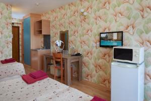 a room with two beds and a kitchen with a tv at Hotel Yantra in Sunny Beach