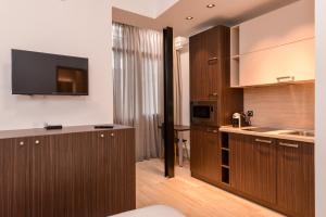 a kitchen with wooden cabinets and a flat screen tv at CACAO Studio next to Crystal Garden and Russian Church in Sofia