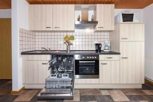 a kitchen with white cabinets and a dishwasher at Haus Hafeneck - Hafennähe - Poolnutzung - Garten - Tischtennis in Bensersiel