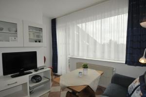 Una sala de estar con un televisor y una mesa. en Apartmenthaus am Watt Büsum, en Büsum