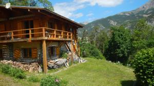 a log house on a hill with mountains in the background at PRA BIQUET in Les Thuiles