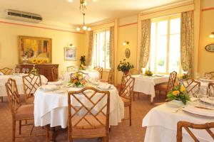 a dining room with white tables and chairs and windows at Logis L'hermitage in Buzançais