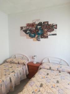 プエルト・デ・マサロンにあるPension La Lineaのベッドルーム1室(ベッド2台付)が備わります。壁に蝶の絵が飾られています。