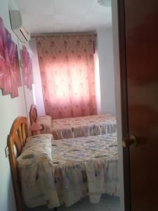 プエルト・デ・マサロンにあるPension La Lineaのピンクの壁のベッドルーム1室(ベッド2台付)