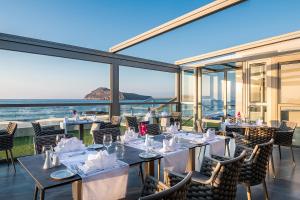 a restaurant with tables and chairs with a view of the ocean at Porto Platanias Beach Luxury Selection - Adults Only in Plataniás