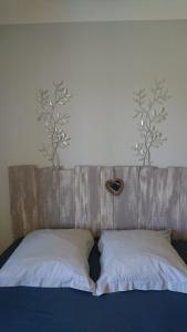 - 2 oreillers sur un lit avec 2 arbres sur le mur dans l'établissement Chambre d'Hôtes Les Bruyères, à Cadouin