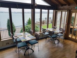 restauracja ze stołami i krzesłami oraz widokiem na ocean w obiekcie Ferry House Inn w mieście Milford Haven