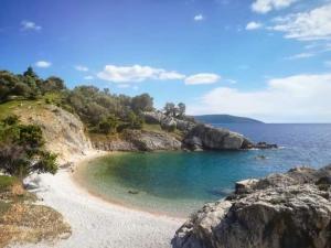 einen Strand mit Felsen, blauem Wasser und Bäumen in der Unterkunft Apartment Gordana in Cres