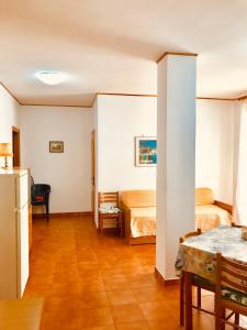 Habitación con 2 camas, mesa y nevera. en Appartamenti Oleandri, en Vieste