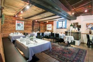 una sala da pranzo con tavoli bianchi e sedie nere di Hotel La Cruna a Sedrun