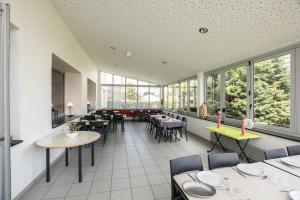 ein Restaurant mit Tischen und Stühlen und Fenstern in der Unterkunft LE SOLEIL DE JADE village vacances in Préfailles