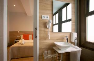 a bathroom with a sink and a bed and a mirror at Hostal Sans in Barcelona