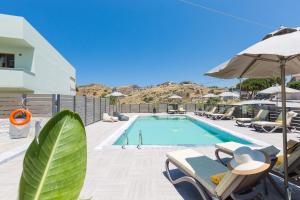 a swimming pool with chairs and an umbrella at Casa Di Kasapa in Panormos Rethymno
