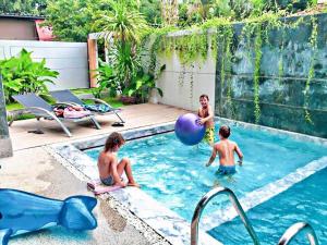 a family playing in a swimming pool in a backyard at Lemonade Phuket Hotel -SHA Plus in Chalong