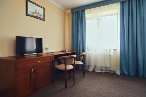 Habitación de hotel con escritorio, TV y ventana. en Hotel Patriarshyi en Leópolis