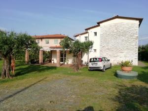 a house with a car parked in a yard at Bed&Breakfast La Zagara in Querceta