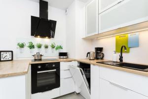 a kitchen with white cabinets and a black stove top oven at Apartments Claro II by Renters in Krakow