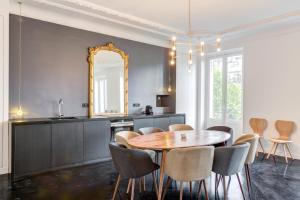 een eetkamer met een tafel en stoelen en een spiegel bij Drouot Luxe in Parijs