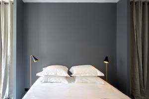 1 dormitorio con paredes azules y 1 cama con almohadas blancas en Drouot Luxe, en París