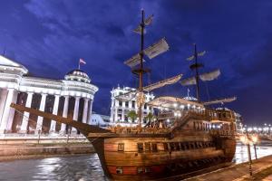 a wooden ship in the water in front of a building at Exclusive-Luxury Mihajlovic Apartment-STRICT&CENTRE in Skopje