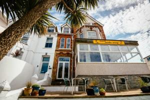 una casa con sedie e una palma di fronte ad essa di Surfside Stop a Newquay Altre 37 foto